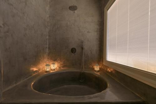 a bathroom with a bath tub with candles and a window at Anemomilos in Oia