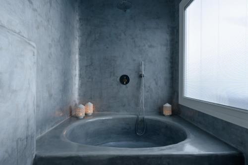 a large bath tub in a bathroom with a window at Anemomilos in Oia