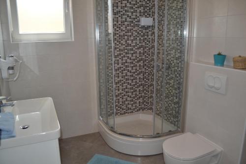 a bathroom with a shower and a toilet and a sink at Apartments Nina in Rab