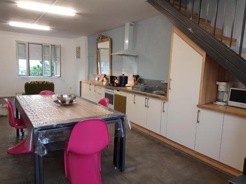 uma cozinha com uma mesa e algumas cadeiras cor-de-rosa em L'Atelier du Tailleur à 5 mn du Puy du Fou em Chambretaud