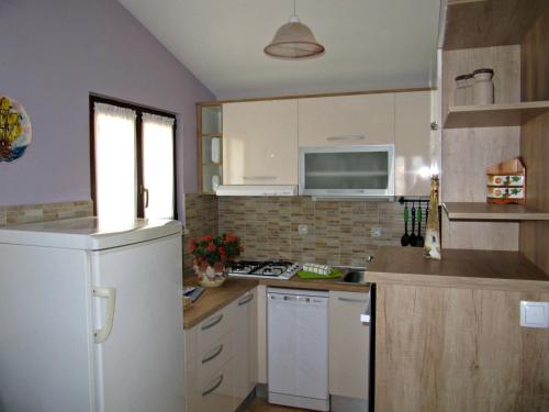 cocina con armarios blancos y nevera blanca en Idea Podstrana, en Podstrana