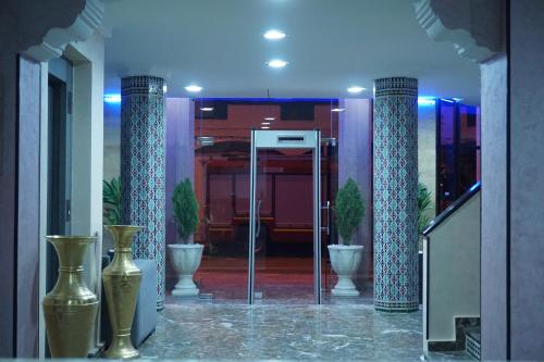 a lobby with three vases and two columns at Hotel Zelis in Asilah