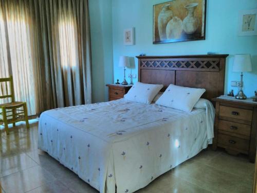 ein Schlafzimmer mit einem großen Bett mit einem hölzernen Kopfteil in der Unterkunft Villa Rural Campillo de Arenas in Campillo de Arenas