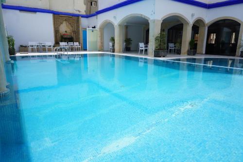 a large swimming pool with blue water in a building at Hotel Zelis in Asilah