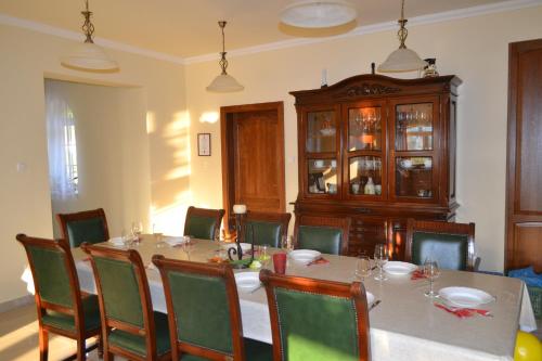 a dining room with a table and chairs and a cabinet at Berezdtető Vendégház in Cserépfalu