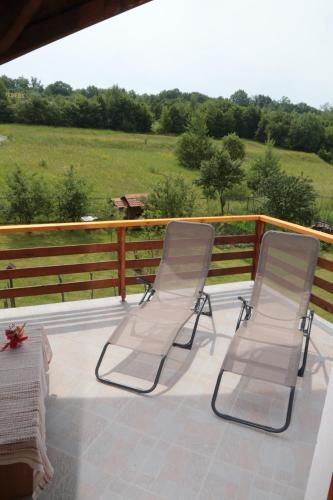 two white chairs sitting on a deck with a fence at Casa Lacul Mierlei in Sovata