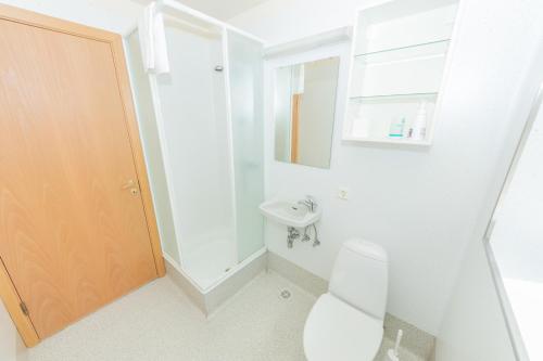 a white bathroom with a toilet and a sink at Hotel Nordurljos in Raufarhöfn