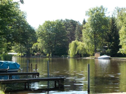 a lake with a dock and a boat in it at Ferienhaus am Langen See in Heidesee