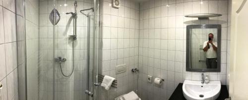 a woman taking a picture of a bathroom at Landhotel Rangau Gasthof & Brennerei in Markt Erlbach