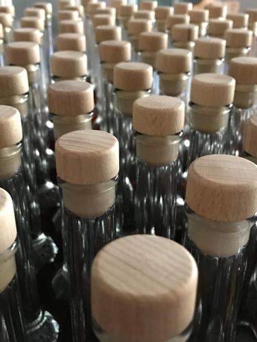 a row of glass bottles with wooden tops in a factory at Landhotel Rangau Gasthof & Brennerei in Markt Erlbach