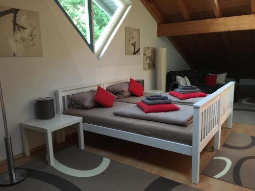Schlafzimmer mit einem Bett mit roten Kissen und einem Fenster in der Unterkunft kleine 5 - feines Wohnen auf Zeit in Karlsruhe