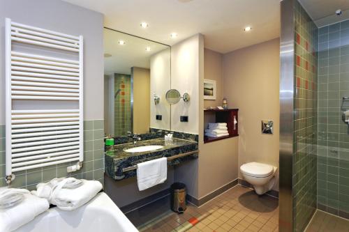 a bathroom with a sink and a toilet and a mirror at Hotel Kaliebe in Trassenheide