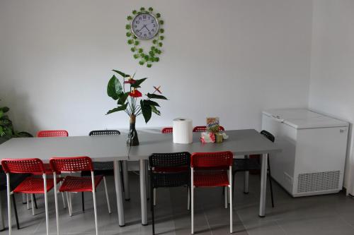 a dining room table with red chairs and a clock on the wall at Complex Turistic Dávid in Boghiş