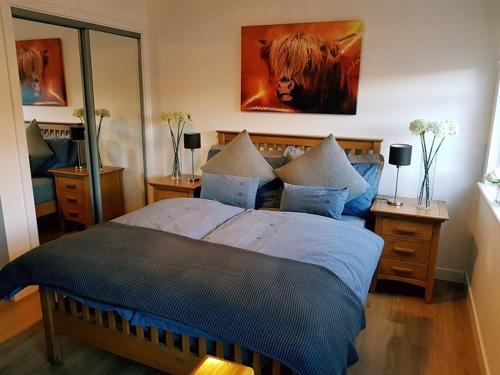 a bedroom with a large bed and a painting on the wall at Yvi's 2Bedroom 2Bathroom Apartment in Inverurie