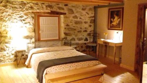 una camera con letto e parete in pietra di B&B Sasso Bianco a Prata Camportaccio