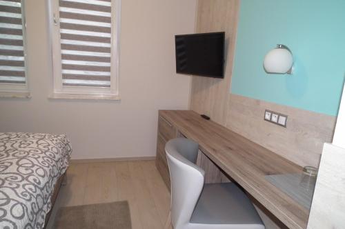 a room with a desk with a television and a bed at Gdanziger Dom in Gdańsk