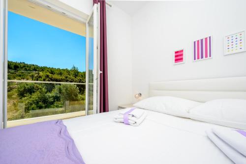 a bedroom with a white bed and a large window at Villa Niki 2 in Cavtat