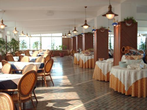 una sala da pranzo con tavoli, sedie e cercatore di tavoli di Eden Beach Club a Torre Canne