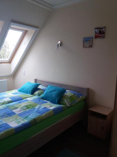 een slaapkamer met een bed met blauwe kussens en een raam bij Tahiti apartman in Hajdúszoboszló