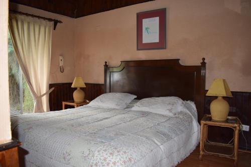 a bedroom with a large bed and two lamps at Hotel Casa de Piedra in Coquimbo