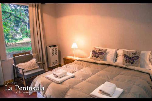 a bedroom with a bed with towels and a window at Hostería La Península in Villa Ventana