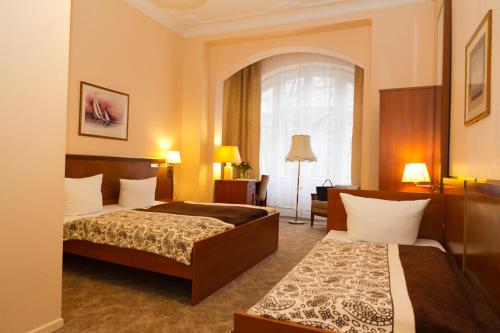 ベルリンにあるホテル アルシュのベッド2台と窓が備わるホテルルームです。