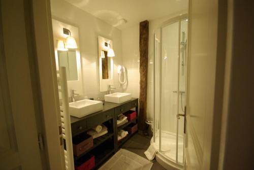a bathroom with two sinks and a mirror and a shower at LogisHotels Le Relais du Quercy in Meyssac