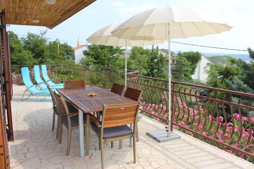 a wooden table with chairs and an umbrella on a balcony at Apartmani Mia in Jadranovo