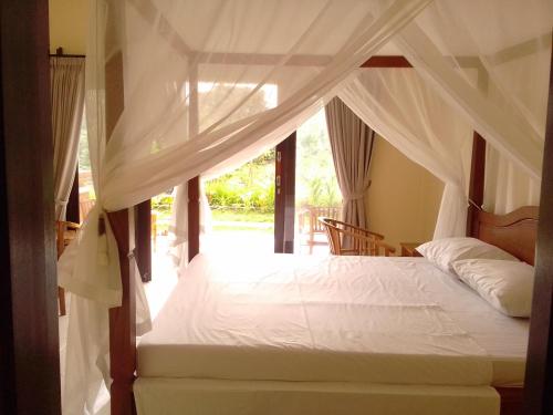 Un dormitorio con una cama blanca con dosel. en Taman Padi Villa, en Amed