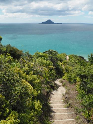 a path leading to the ocean with a mountain in the background at Whakatane Hotel in Whakatane