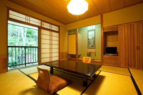 uma sala de estar com uma mesa de vidro e uma televisão em Kurokawa Onsen Oku no Yu em Minamioguni