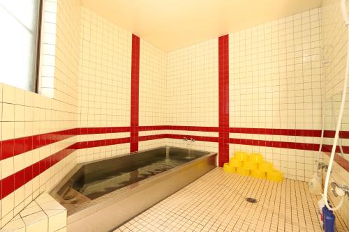 a bathroom with a tub in a red and white tiled wall at Hachikogen Furusato Asagiriso in Yabu