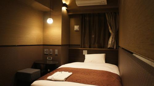 a small room with a bed and a window at Hotel SUI Ginza Kyobashi by ABEST in Tokyo