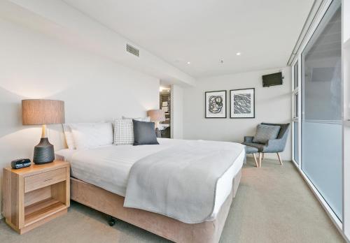 a bedroom with a bed and a table with a lamp at Sullivans Cove Apartments in Hobart