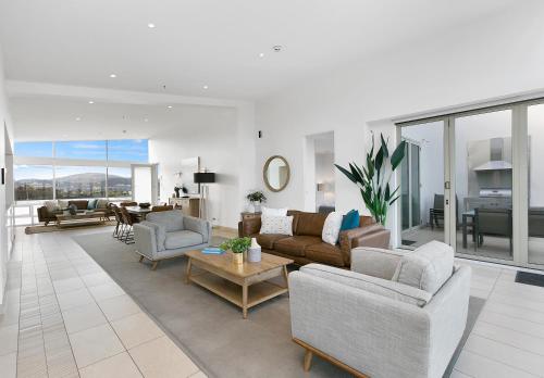 uma sala de estar com um sofá, cadeiras e uma mesa em Sullivans Cove Apartments em Hobart