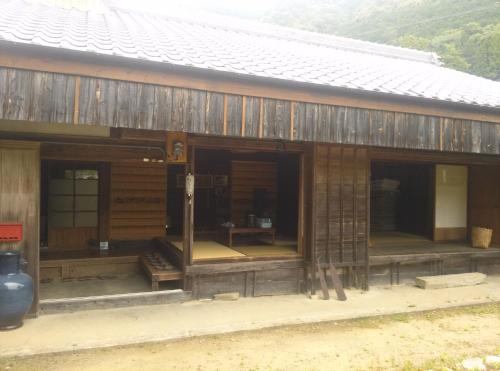 a large wooden building with windows and a roof at Guesthouse Okagesan in Hongu