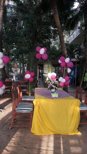 a table with a yellow table cloth and flowers on it at Tony Home and Restaurant in Karon Beach