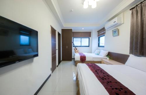 a hotel room with two beds and a flat screen tv at Guitar Charm B&B in Wujie