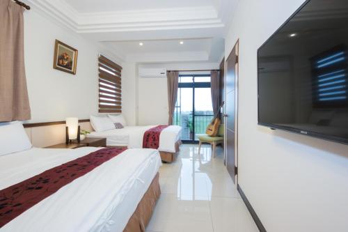 a hotel room with two beds and a flat screen tv at Guitar Charm B&B in Wujie