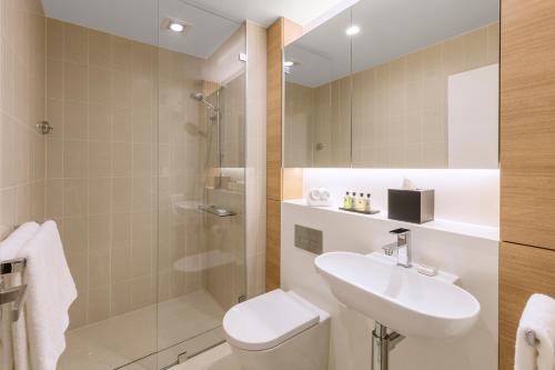 a bathroom with a sink, toilet and bathtub at SKYE Hotel Suites Parramatta in Sydney