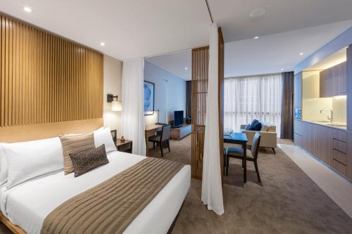 a bedroom with a large bed and a living room at SKYE Hotel Suites Parramatta in Sydney