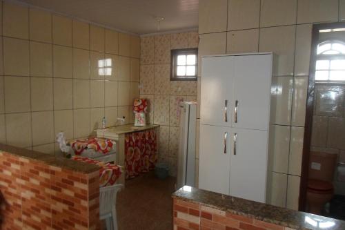 Il comprend une cuisine équipée d'un réfrigérateur blanc et d'une table. dans l'établissement Quitinetes dos Ipês, à Barra de São João