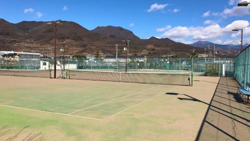 a tennis court with mountains in the background at Kasugai View Hotel in Fuefuki