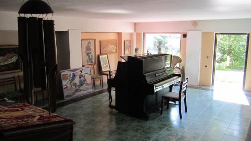 a living room with a piano and a room with paintings at Dili Villa in Dilijan