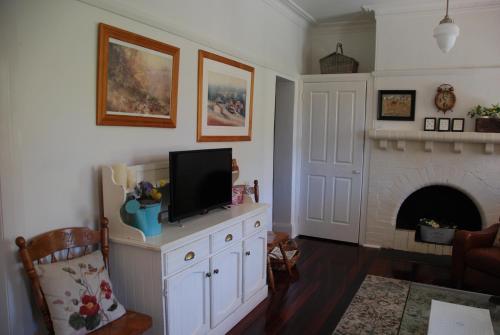 a living room with a tv and a fireplace at Hillside Cottage Berrima in Berrima