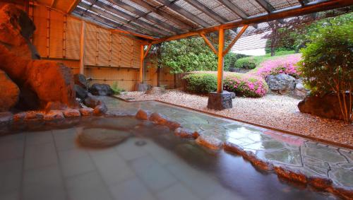a swimming pool in a garden with a waterfall at Kasugai View Hotel in Fuefuki