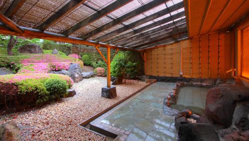 a garden with a pond and a pergola at Kasugai View Hotel in Fuefuki