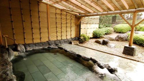 a swimming pool in a building with a wooden roof at Kasugai View Hotel in Fuefuki