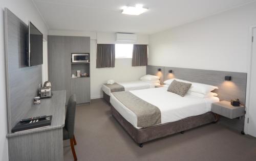 a hotel room with two beds and a desk at Bridge Hotel in Smithton