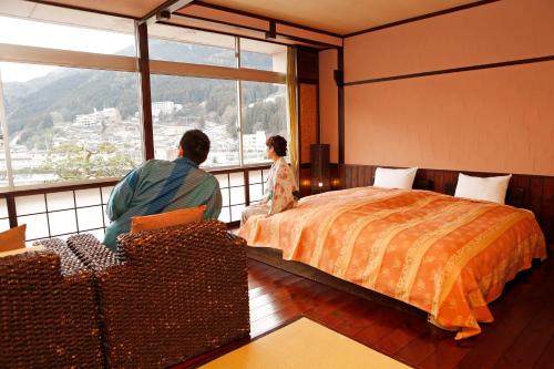 a man and a girl sitting in a room with a bed at Bosenkan in Gero